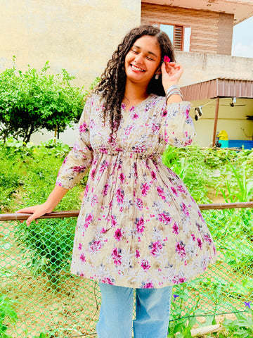 Woman in a floral dress standing outdoors with greenery in the background