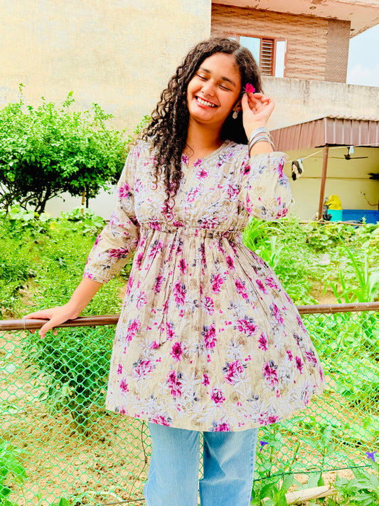 Woman in a floral dress standing outdoors with greenery in the background